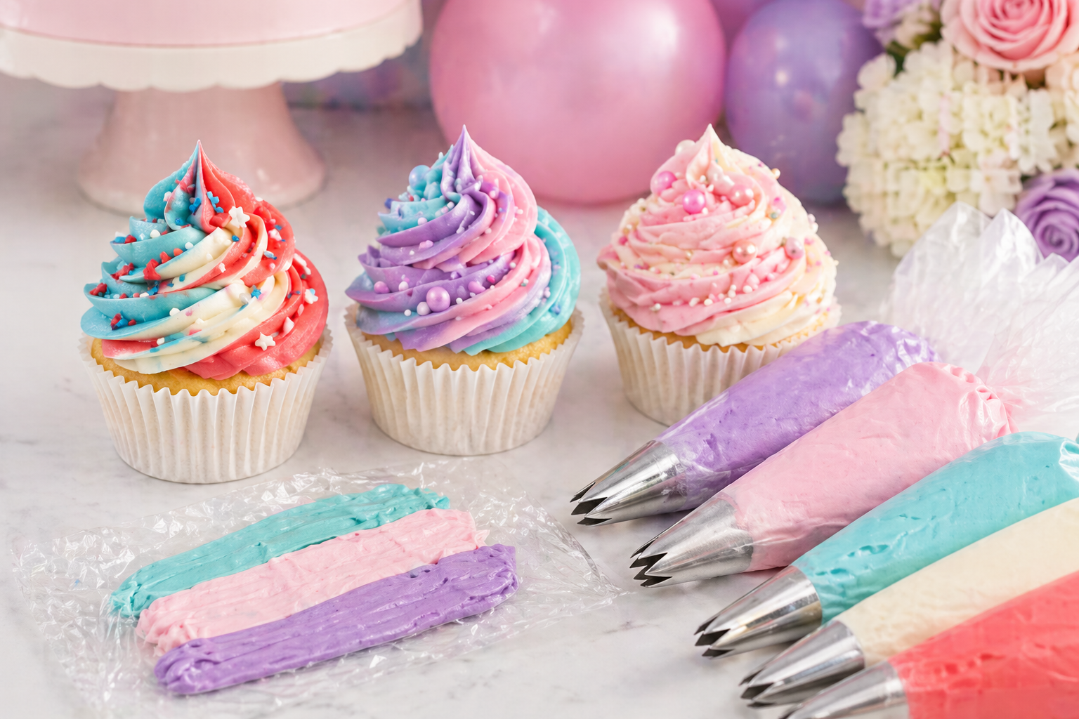 Multi-coloured buttercream cupcakes with swirls in teal, pink and purple on a styled party dessert table in Sittingbourne