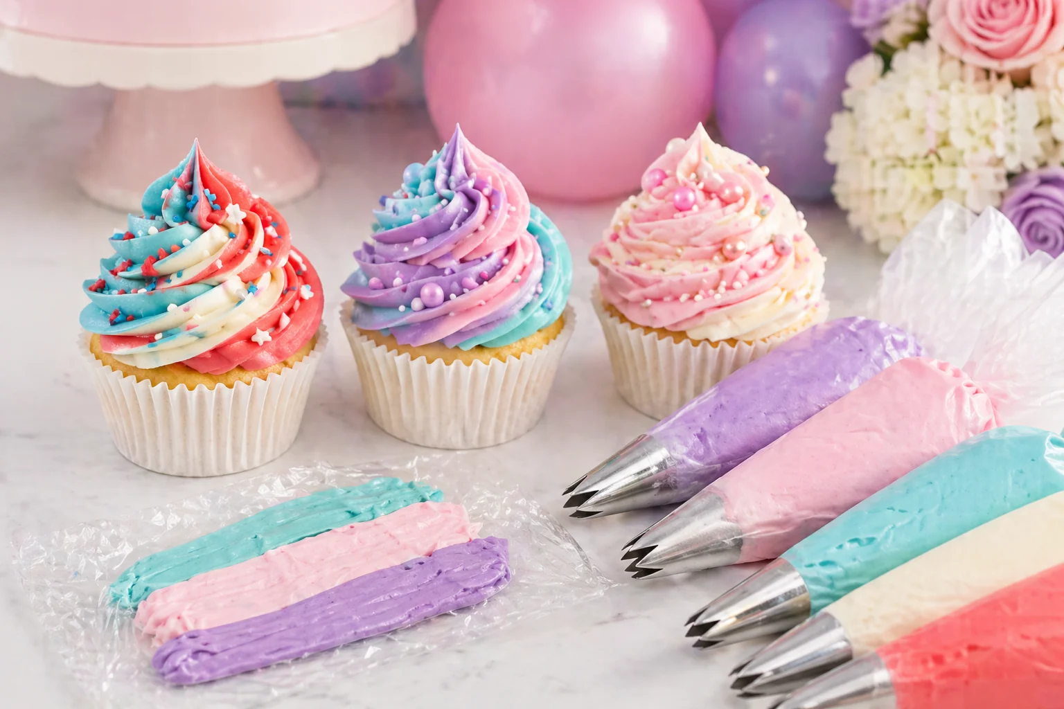 Multi-coloured buttercream cupcakes with swirls in teal, pink and purple on a styled party dessert table in Sittingbourne